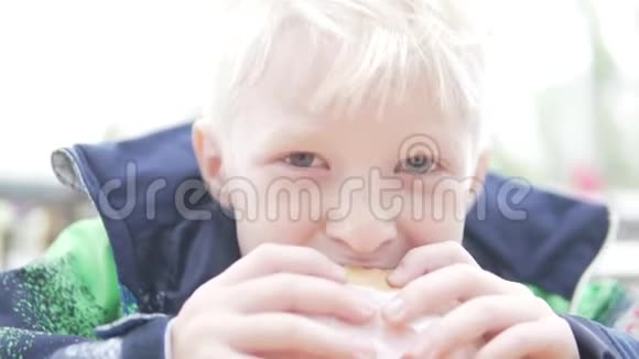饥饿的男孩在街上吃汉堡包视频的预览图