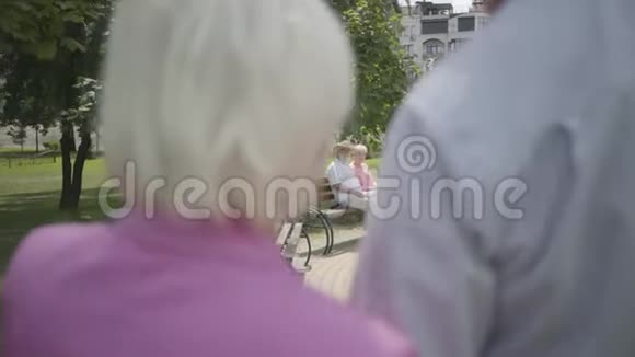两对可爱的成熟夫妇在公园里相遇双人约会的高级夫妇老人和女人互相问候伙计视频的预览图