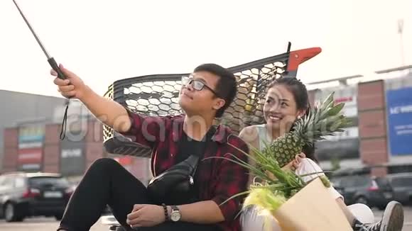 漂亮的30多岁的亚洲女人手里拿着苹果和她迷人的男朋友坐在沥青上做着视频的预览图