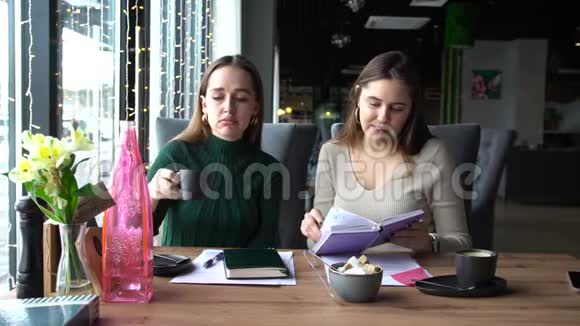 两个年轻的女商人在咖啡馆喝咖啡讨论工作视频的预览图