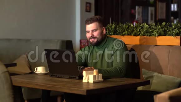 商务人士使用笔记本电脑一边喝咖啡一边在咖啡馆工作一边微笑视频的预览图