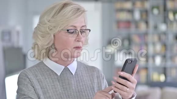 悲伤的老女人回应智能手机丢失的画像视频的预览图