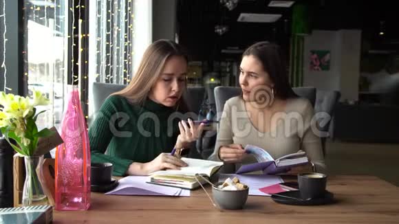 两个年轻的女商人正坐在咖啡馆里和一个说话的伙伴交谈视频的预览图