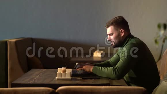 这个人对所做的工作很满意快乐的年轻人坐在咖啡馆里用笔记本电脑工作视频的预览图