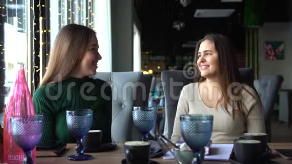 两个活泼可爱的年轻女人在咖啡馆里谈笑风生视频的预览图