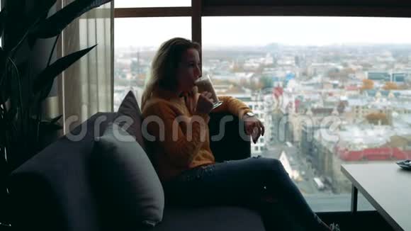 一位女士正在喝咖啡看着窗外的城市景色视频的预览图