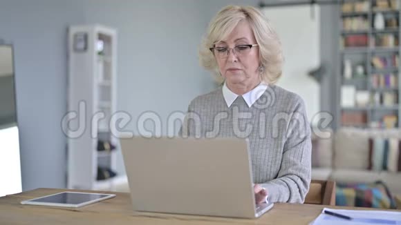 现代办公室使用笔记本电脑的严肃老妇人视频的预览图