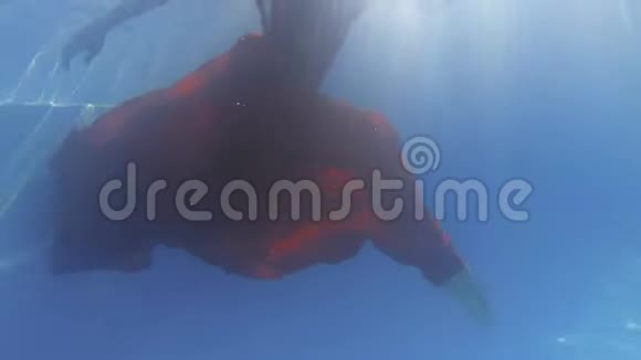 穿红色衣服的年轻女子优雅地在水下移动双腿视频的预览图