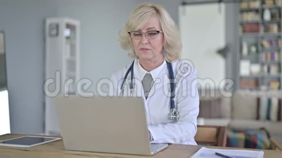 老女医生用手提电脑对着镜头微笑视频的预览图
