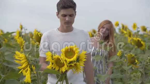 那个年轻的女人和男人在户外玩得很开心他的女朋友站着的时候把向日葵抱在前台视频的预览图