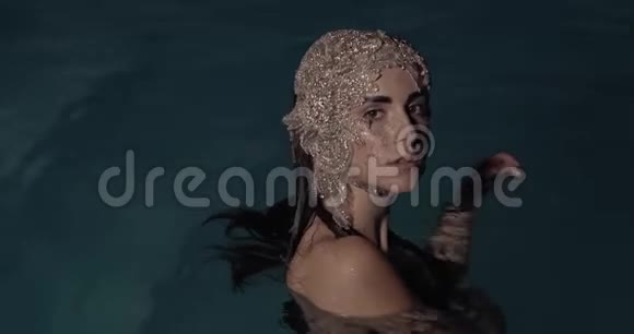 一位棕色眼睛的年轻女子戴着一顶由游泳池里的珠宝制成的帽子4K视频的预览图