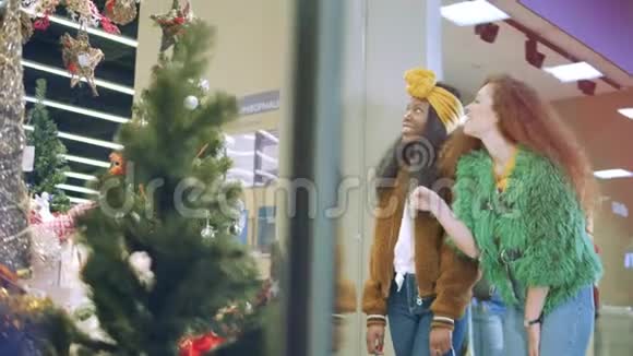 女孩们在商场里看商店橱窗上面有节日装饰视频的预览图