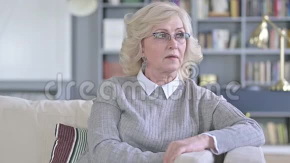 美丽的老妇人坐在沙发上环顾四周视频的预览图