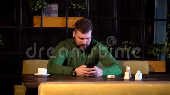 大胡子男手持手机用现代相机拍照视频的预览图