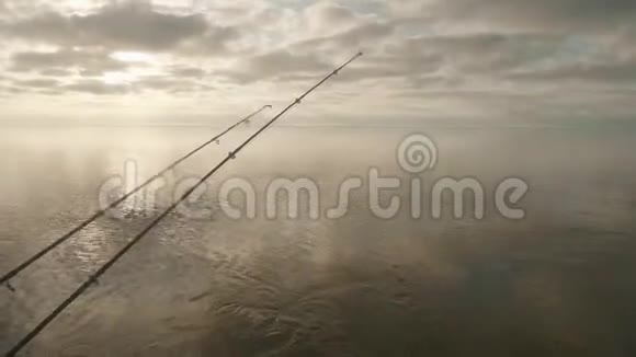 三根鱼竿在水面上的景色钓船上挂着尖嘴多云的天空在背景上视频的预览图
