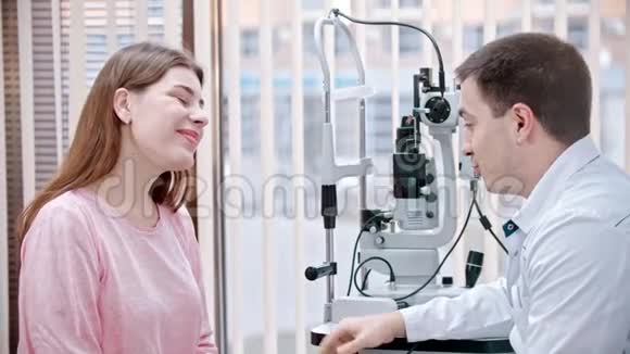 橱柜里的眼科治疗年轻微笑的女人正在和验光医生协商视频的预览图