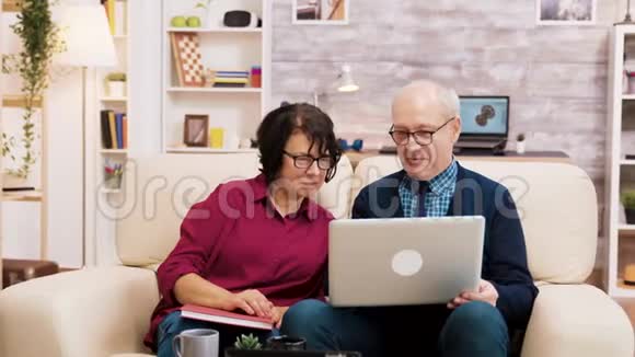 一对老人坐在沙发上用手提电脑上网购物视频的预览图