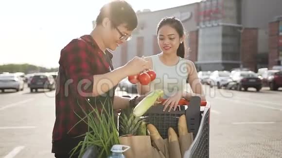 年轻的亚洲男人和女人看着他们在超市买的产品视频的预览图