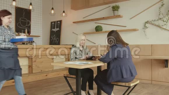咖啡厅女服务员用平板电脑为女性提供咖啡视频的预览图