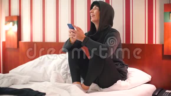 一个快乐的女人坐在旅馆的床上视频的预览图