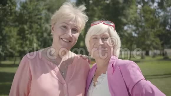 两个微笑可爱的女人看着相机微笑站在夏天公园的肖像户外休闲成熟成熟视频的预览图