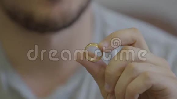 一幅未被认出的留着胡子的男人坐在家里拿着金色结婚戒指的肖像他要提出一个建议视频的预览图