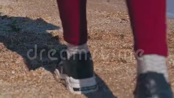 一个穿运动鞋的少年在海滩上靠近水的特写镜头视频的预览图