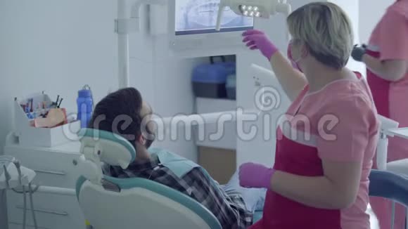 牙医戴着医用口罩和手套用镜子检查病人的嘴带仪器的助理视频的预览图