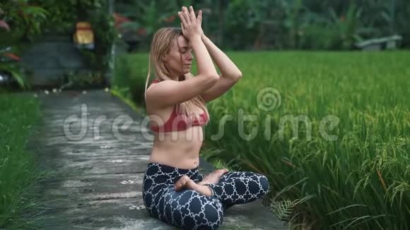年轻女性做瑜伽运动户外冥想背景绿色植物视频的预览图