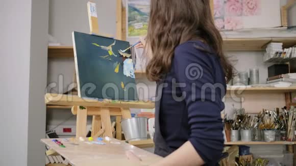 从工作室里的女艺术家的背影看用染料画一幅画视频的预览图