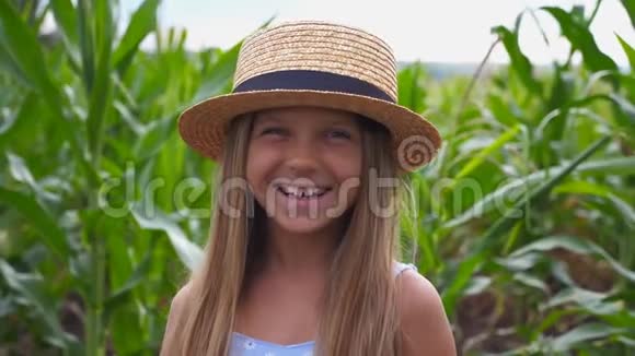 戴着草帽的漂亮滑稽女孩的肖像看着镜头笑着用手捂住脸快乐的小家伙视频的预览图