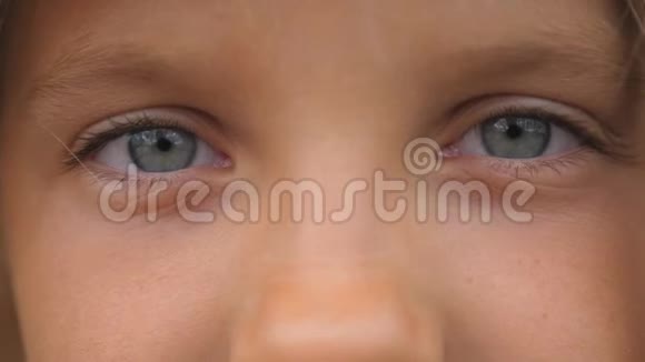 美丽的小女孩的蓝眼睛眨着眼睛带着悲伤的目光看着镜头年轻可爱的脸庞肖像视频的预览图