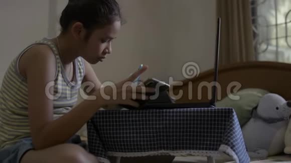 亚洲可爱的女孩穿着单身衬衫在网上看课在床上做作业女青少年在家学习视频的预览图