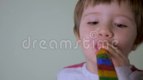 那个嘴里吐着舌头的男孩的肖像快乐的男孩带着节日的哨子玩得很开心孩子的特写镜头视频的预览图