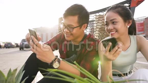 好看的亚洲年轻人坐在地上手里拿着食物和手机的纸袋视频的预览图