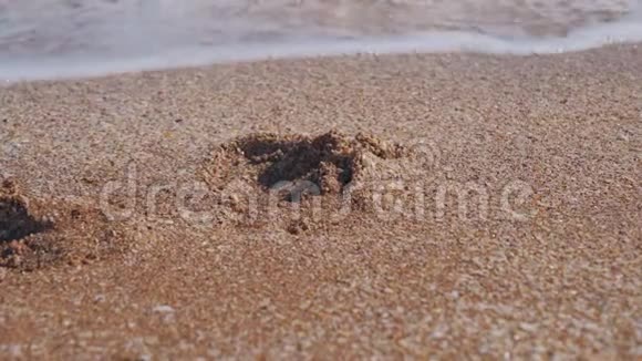 轻波冲刷沙中的脚印视频的预览图