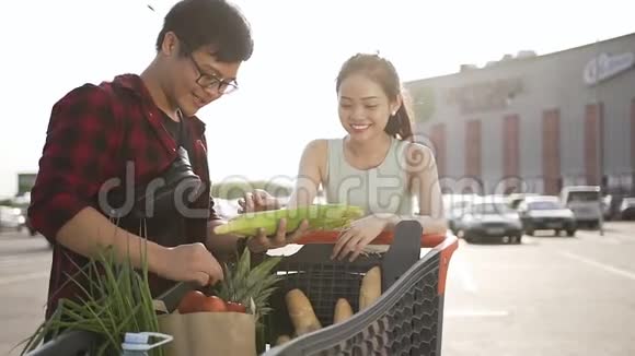 英俊的越南男人给她可爱的女朋友展示了从市场手推车出来的玉米和西红柿视频的预览图