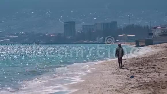 穿着暖和衣服的女孩沿着城市附近的海滩散步视频的预览图