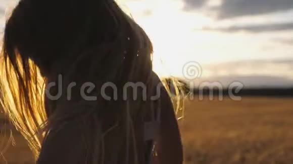 日落时分欢乐的微笑女孩在迷离的大麦地背景下跳跃开心的笑孩子视频的预览图
