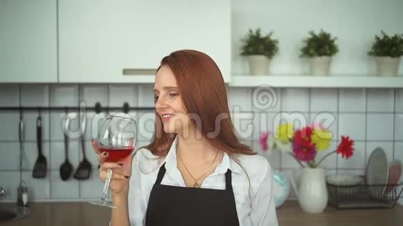年轻女性在家庭厨房喝酒红头发的人关门了视频的预览图
