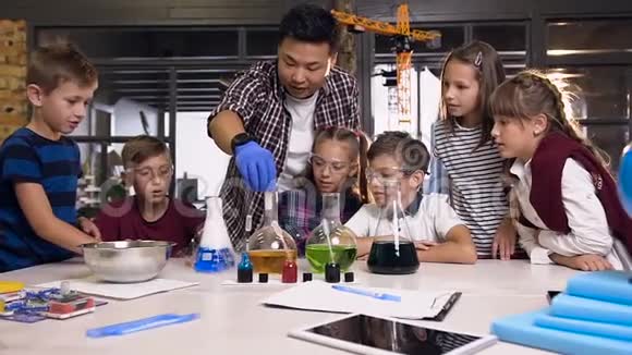 亚洲科学老师带着实验室班的孩子用彩色液体把干冰放进烧瓶里做实验视频的预览图