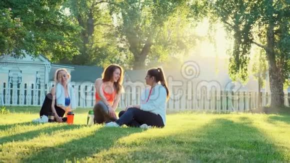 三个女朋友正坐在草地上慢跑后笑着说话视频的预览图