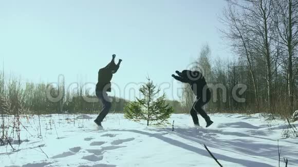 两个男人围着圣诞树在冬天的田野里跳舞和胡闹迎接新年的概念视频的预览图