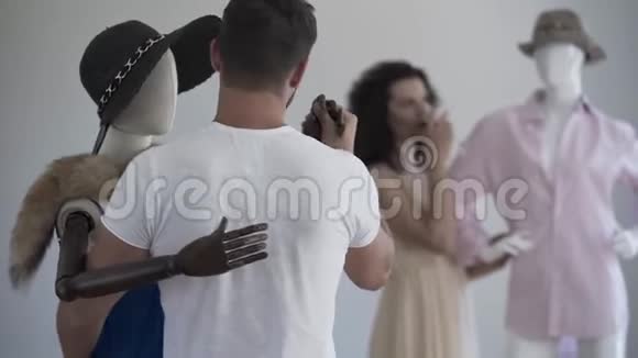 从后景看英俊的男人和戴着帽子的女模特跳舞而女人在后台喝酒视频的预览图