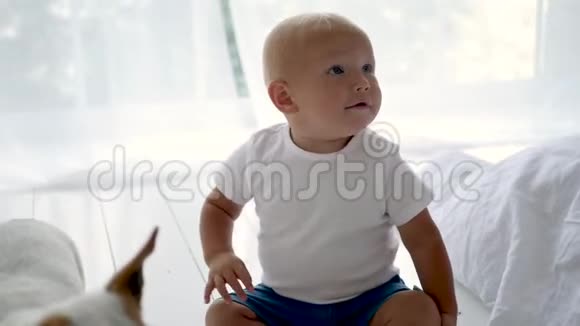 穿着白色T恤的孩子坐在白色房间的地板上视频的预览图