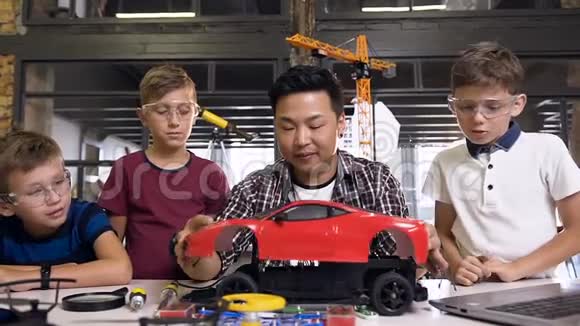 年轻的韩国电子工程师带着年幼的孩子用螺丝刀拆卸机器人机器视频的预览图