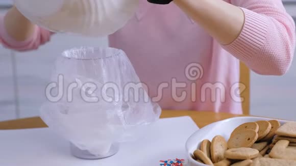 女人手把糖糖糖霜放在碗里用来装饰饼干和姜饼屋烹饪视频的预览图
