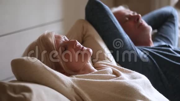 平静的中年夫妇放松地靠在舒适的沙发上视频的预览图