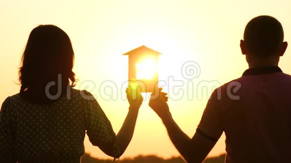 一男一女抱着纸房看夕阳幸福家庭的剪影普伦纳普家庭视频的预览图