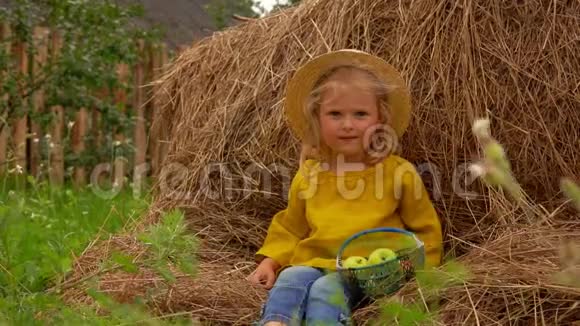 可爱的女孩拿着篮子坐在干草堆上视频的预览图